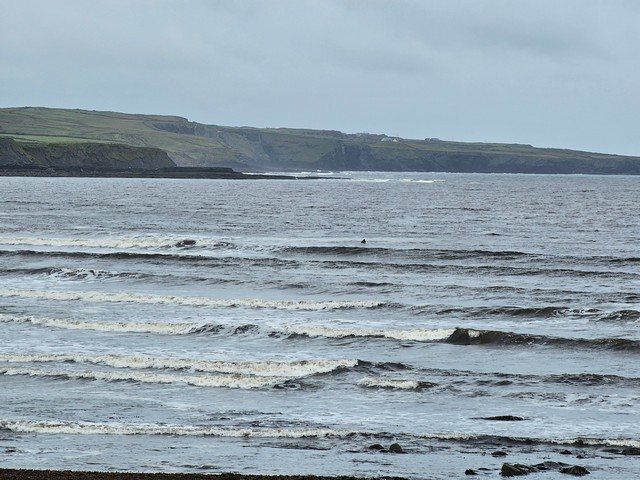 A set breaking at cornish point as a surfer eyes up further waves